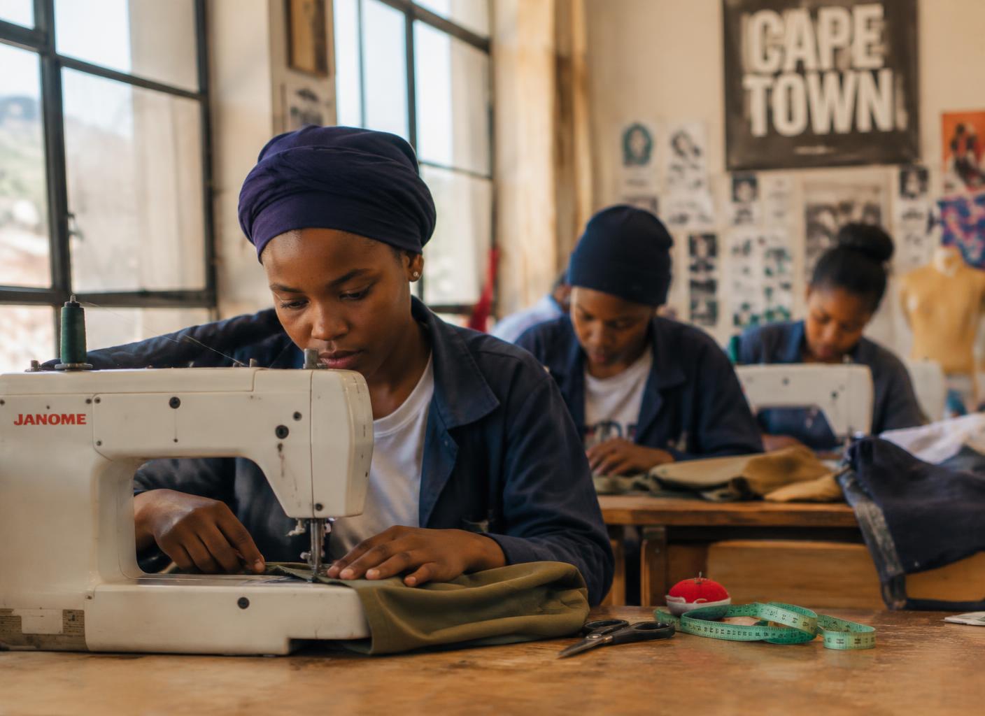 AI-generated illustration of young trainees sewing in a Cape Town textile workshop